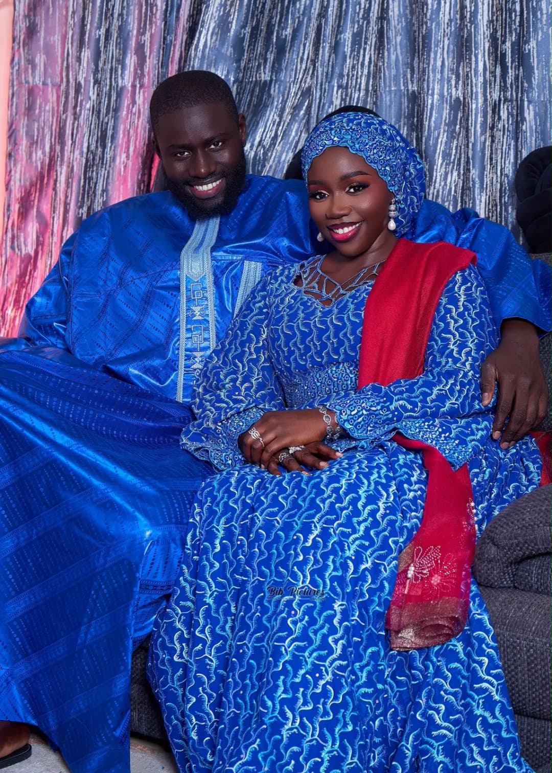 Couple assis et souriant, en grand boubou bleu, tenues de Tabaski.