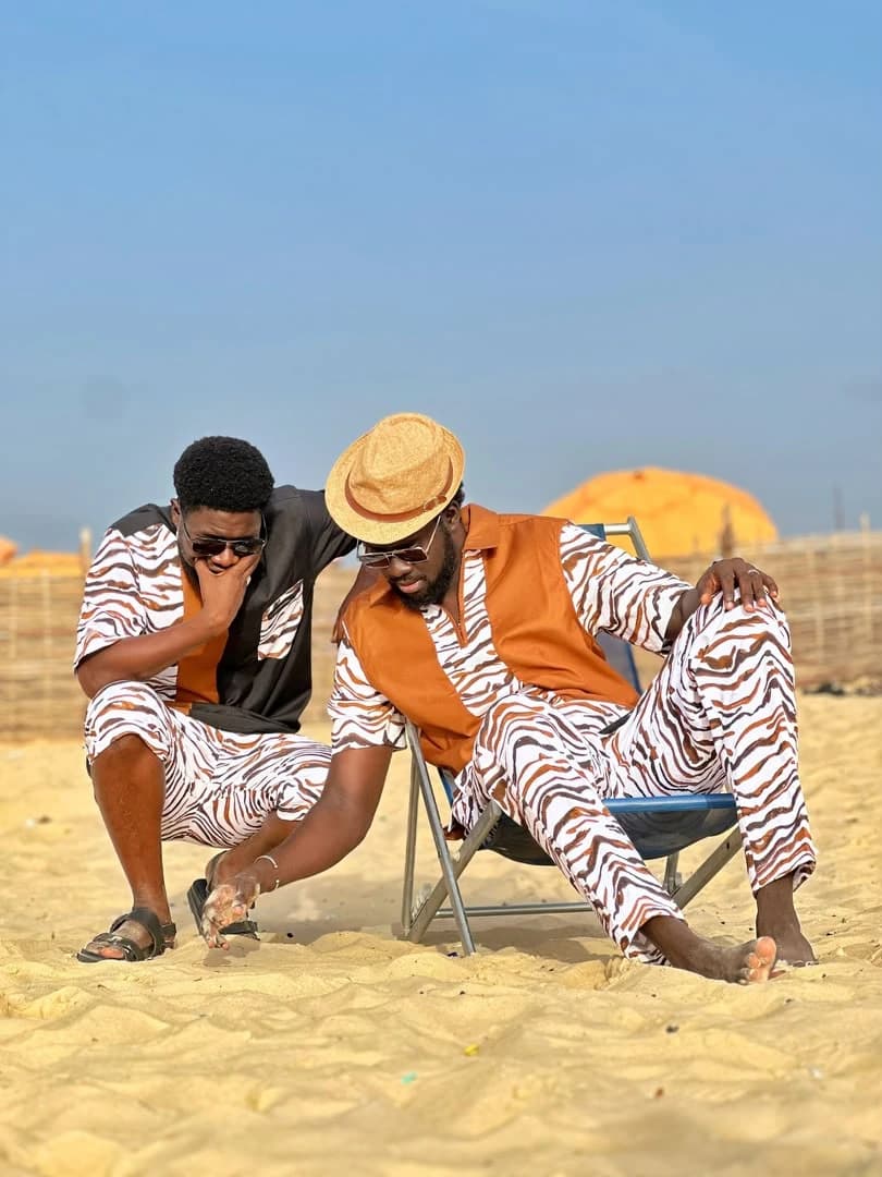BIB, au chapeau de paille sur sa chaise, et son binôme accroupi à ses côtés, sur une plage de Dakar.