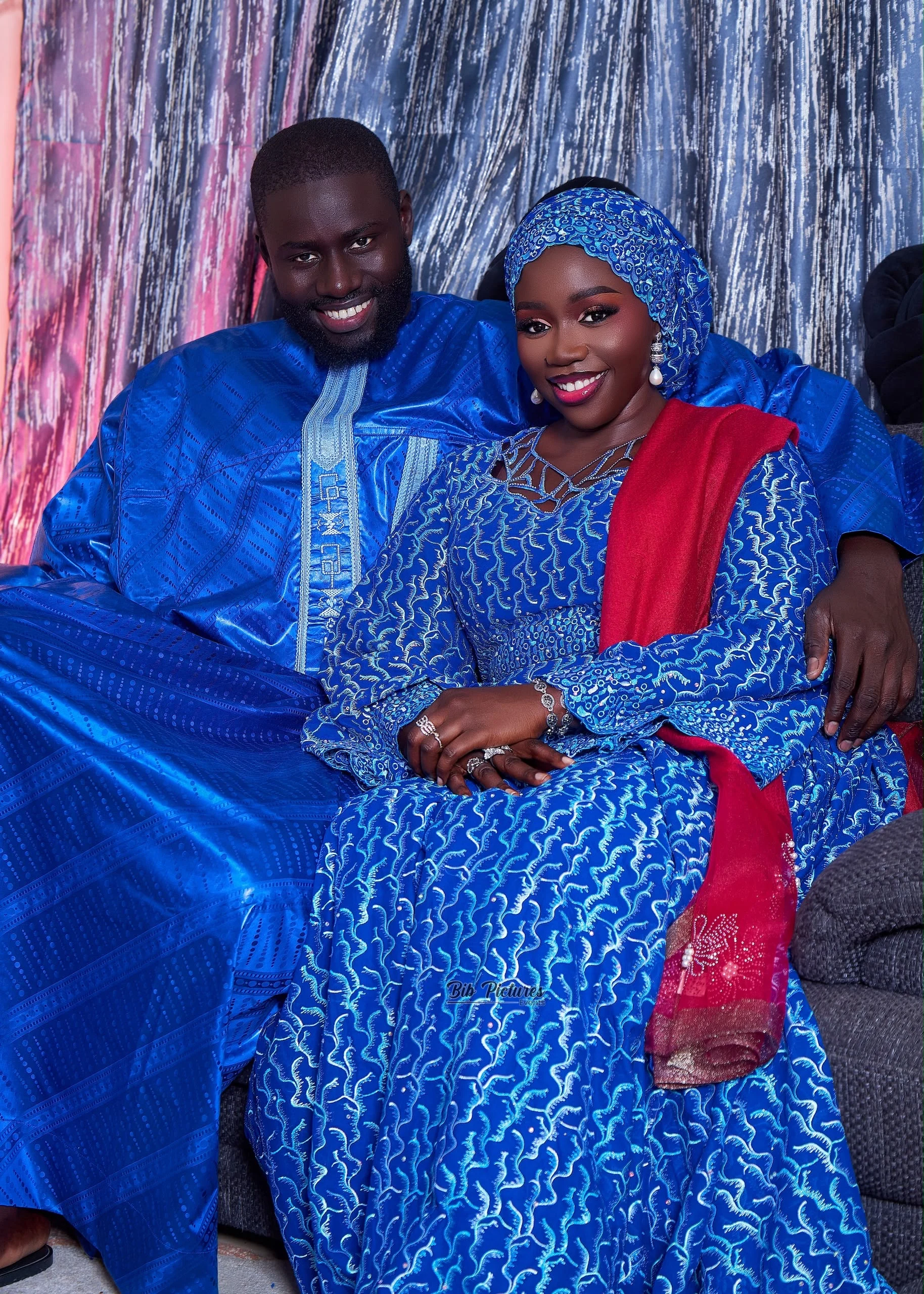 Couple assis et souriant, en grand boubou bleu, tenues de Tabaski.